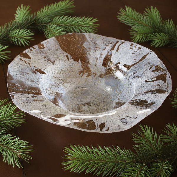 Decorative glass bowl with a textured surface on a dark background with greenery