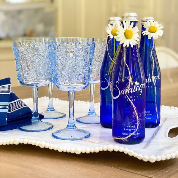 Beatriz Ball white melamine tray with pearl edge, shown with blue acrylic wine glasses and blue bottles of Saratoga water, rectangular handled Alegria Collection melamine tray by Beatriz Ball.....