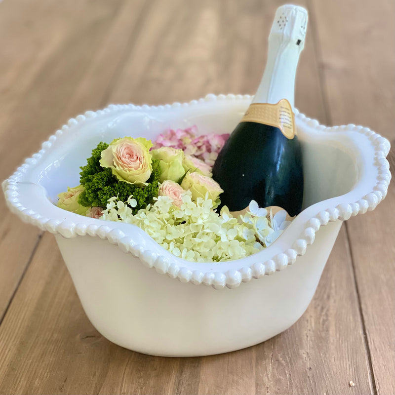 Luminous white melamine ice bucket by Beatriz Ball is shown filled with a bottle of  champagne and fresh flowers.