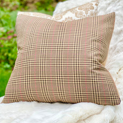 The tailored Brummell black, tan and berry red glen plaid square pillow, sitting on a creamy white faux fur throw.